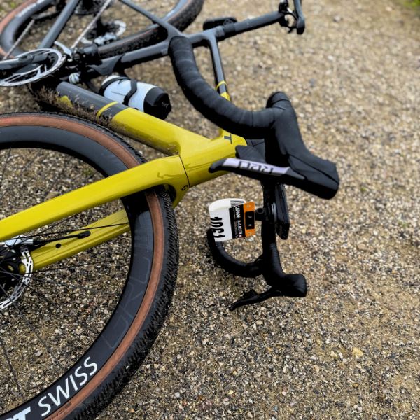 Race number plate mounted on gravel bike handlebar using GoPro adapter mount